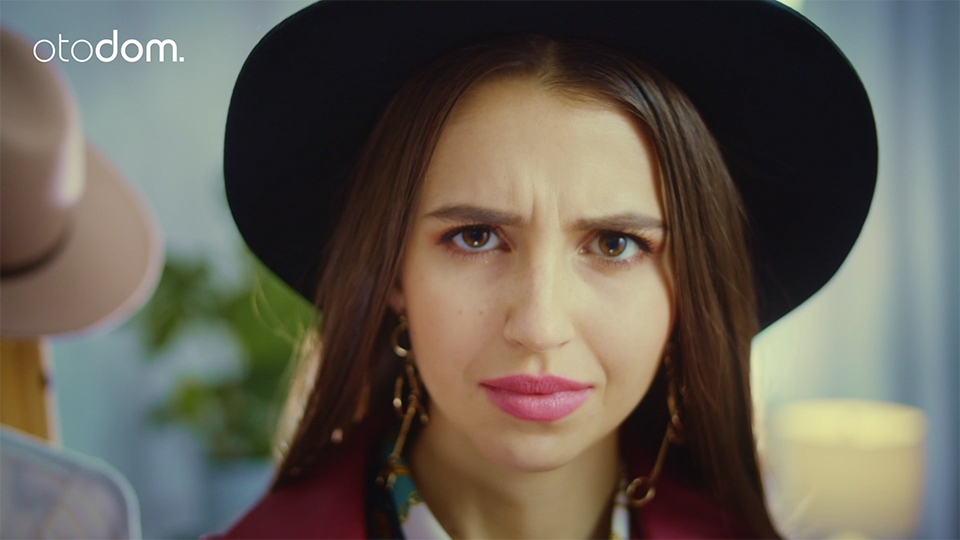 a close up on the face of a young woman wearing a hat frowning, a still from online video for otodom